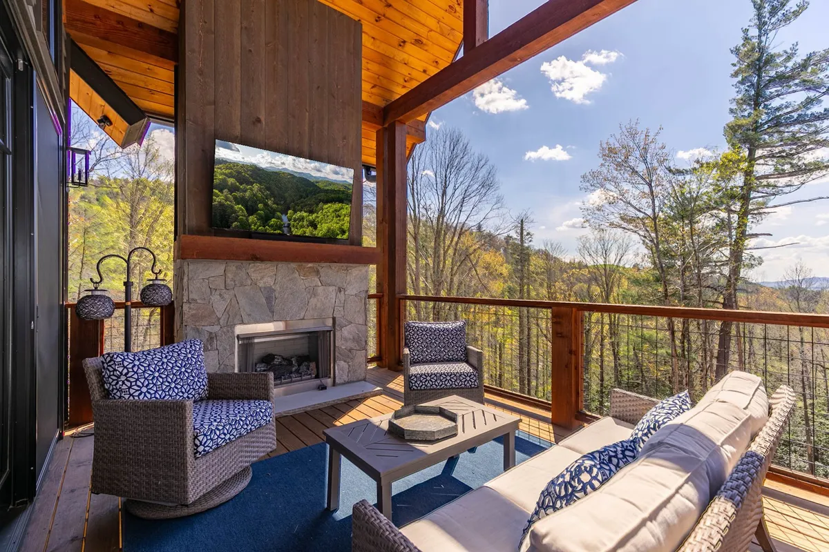 An outdoor seating area anchored by a stone fireplace, comfortable chairs, and decorative lanterns, with sweeping mountain views in the background. The space is ideal for socializing, enjoying sunset dinners, and cozy evenings by the fire.