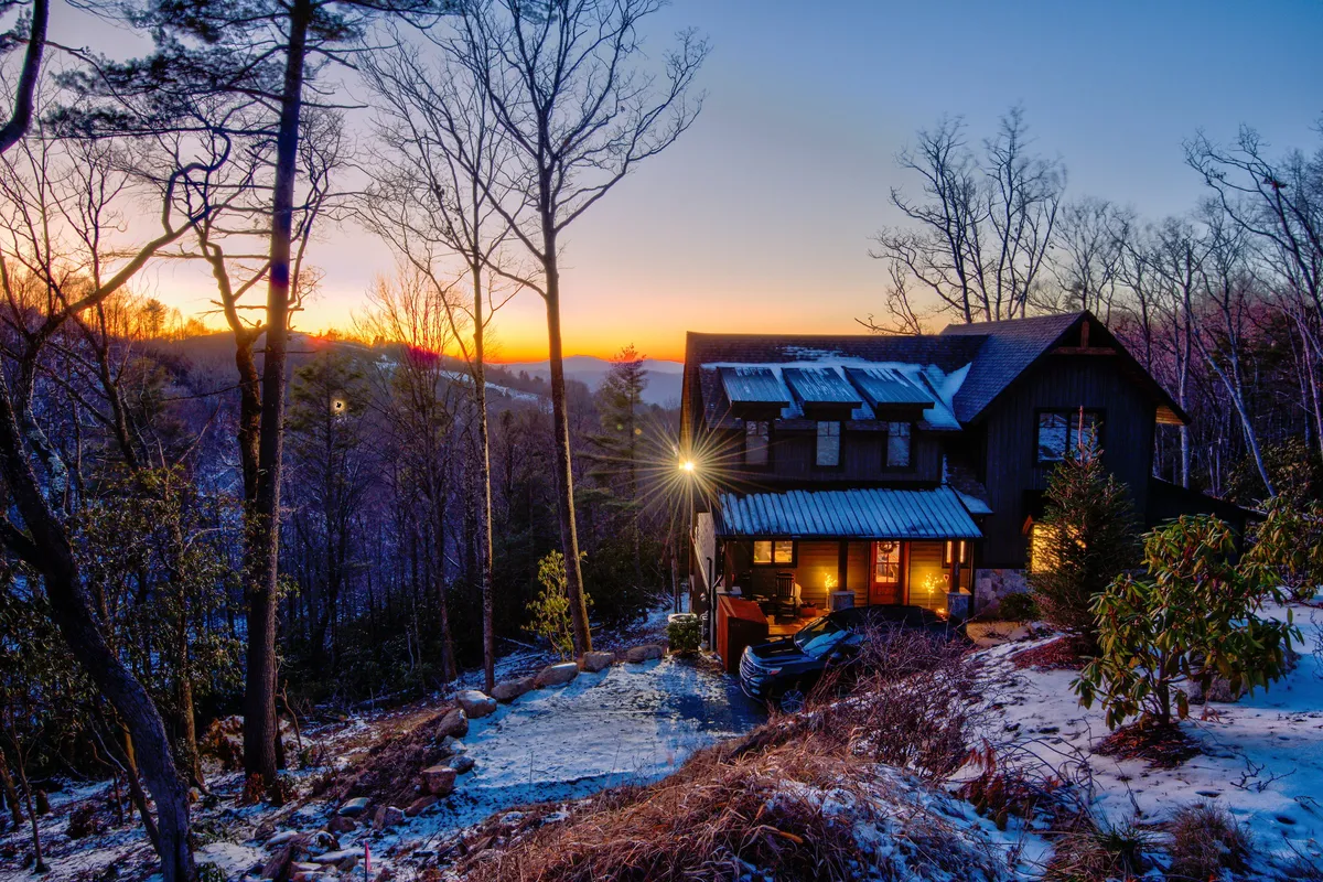 A captivating exterior shot of the house at sunset, with a glowing sky, inviting pathway, and surrounding trees. The scene evokes serenity and the anticipation of adventure.