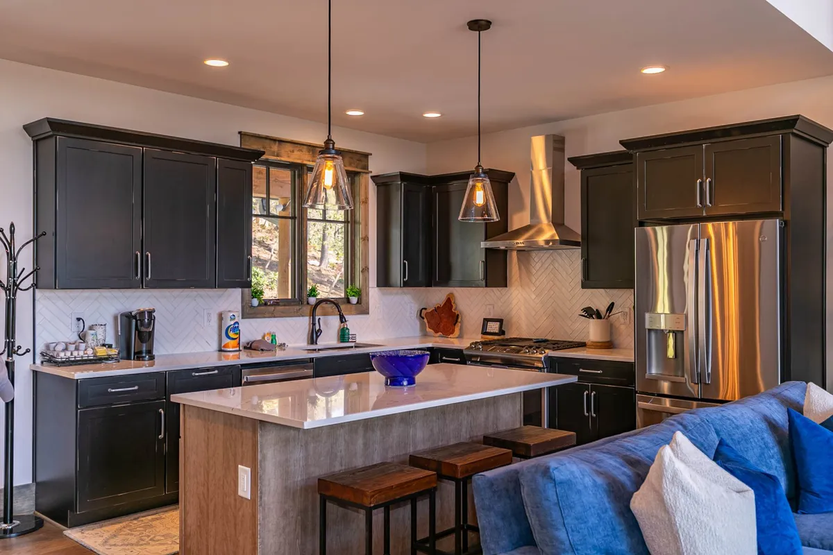 A stylish kitchen scene featuring a central island with modern bar stools, a window offering natural light and views, and contemporary appliances. The setup is ideal for socializing during meal prep and enjoying casual snacks or drinks at the bar.